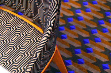 Modern design pattern or abstract textures on armchair in contrast to geometrical shapes on carpet...