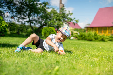 Obraz premium a little boy is lying on the grass and holding a pear