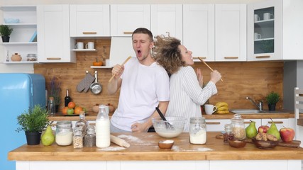 Young Joyful Couple Having Fun Dancing And Singing In Kitchen At Home