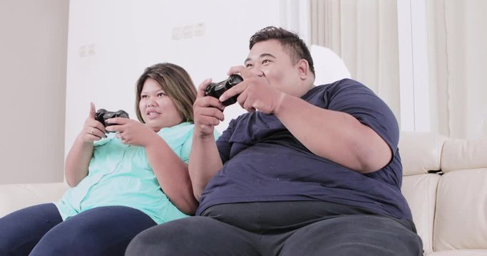 Overweight couple playing video games at home