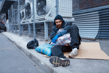 Fototapeta na wymiar Male bearded beggar lies on city street