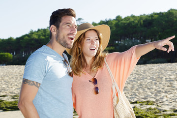 a happy couple pointing the beach