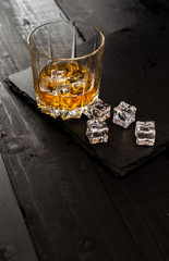 glass of whiskey and ice on wooden table