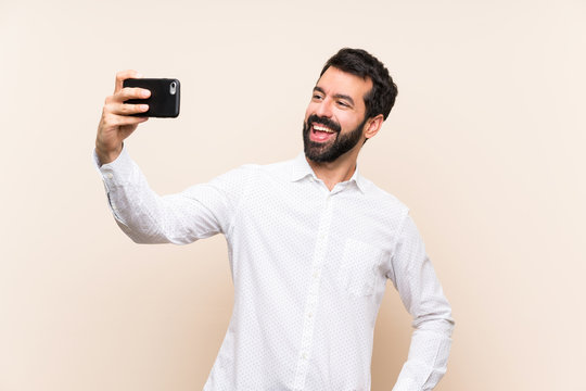 Young man with beard holding a mobile making a selfie