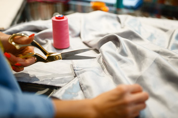 Seamstress cuts fabric with scissors in store