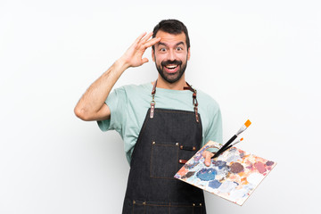 Young artist man holding a palette over isolated background has just realized something and has...