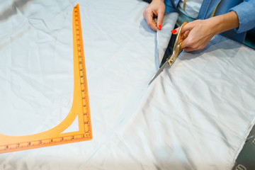 Seamstress cuts fabric with scissors in workshop