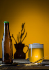 Glass pint of beer close-up with froth over yellow background