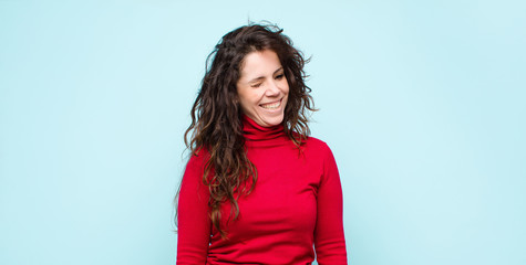 young pretty woman looking happy and friendly, smiling and winking an eye at you with a positive...
