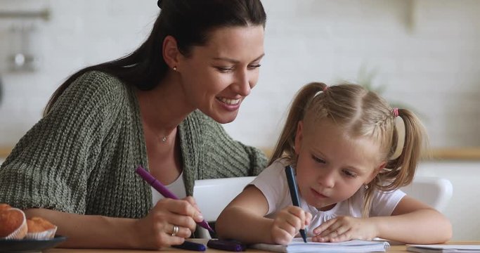 Smiling young woman drawing with little daughter.