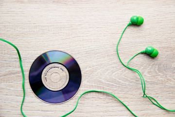 Flat Lay. Green headphones disk are on beige wooden background