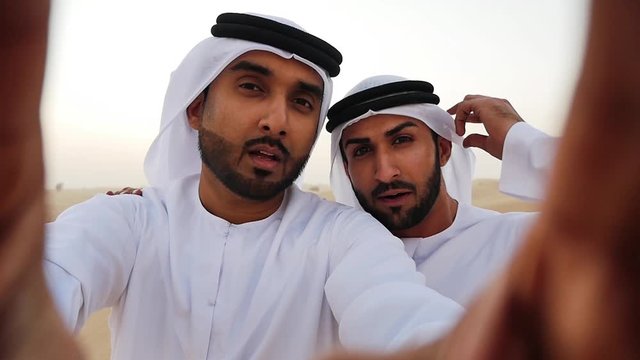 Two men with emirates white kandura traditional outfit making safari in the desert of Dubai