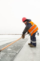 Worker rafts ice blocks along a canal carved in a frozen lake
