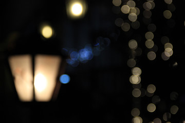 Blurred lantern out of focus in the street at night in the dark. Yellow and blue lights out of focus. Bokeh. Background. Texture for the design