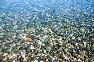 Sea stones in sea water. Pebbles under water. The view from the top. Nautical background. Clean sea water. Transparent sea