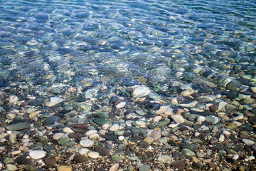 Sea stones in sea water. Pebbles under water. The view from the top. Nautical background. Clean sea water. Transparent sea