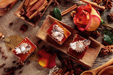 Layered cakes with cinnamon, anise, coffee beans and nuts on a old wooden table.