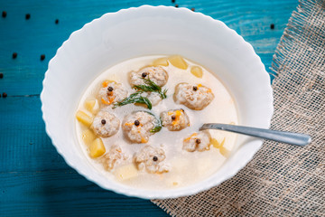 Plate of vegetable soup with meatballs on the wooden table closeup