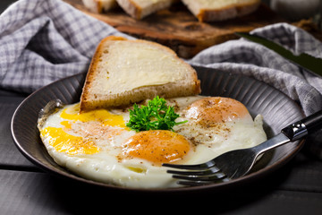 Fried eggs and bread for breakfast on a gray background.