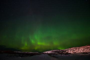Fototapeta na wymiar hills, clear starry sky and colorful Northern lights, an incredible natural phenomenon