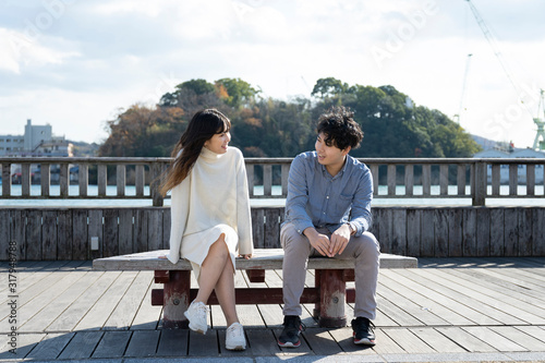 ベンチに座り楽しそうに会話をする若いカップル Wall Mural West Photo