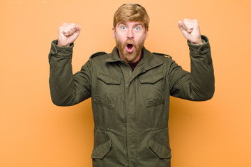young blonde man celebrating an unbelievable success like a winner, looking excited and happy...
