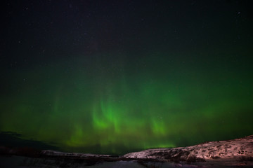 Fototapeta na wymiar hills, clear starry sky and colorful Northern lights, an incredible natural phenomenon