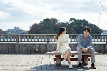 ベンチに座り楽しそうに会話をする若いカップル Wall Mural West Photo