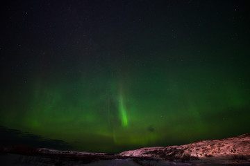 hills, clear starry sky and colorful Northern lights, an incredible natural phenomenon