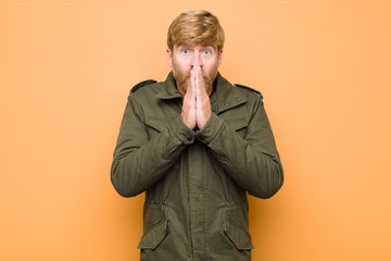 young blonde man happy and excited, surprised and amazed covering mouth with hands, giggling with a...