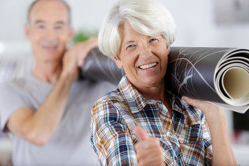 happy mature couple carrying carpet