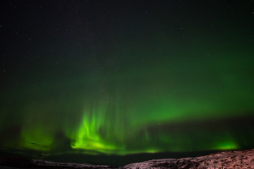 hills, clear starry sky and colorful Northern lights, an incredible natural phenomenon