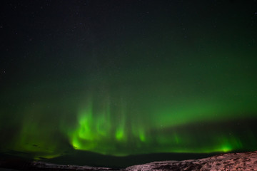 hills, clear starry sky and colorful Northern lights, an incredible natural phenomenon