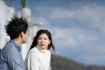 Fototapeta premium 堤防に腰掛け楽しそうに会話をする若いカプル