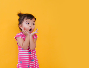 Portrait of cute little asian girl is shouting with beuatiful face over yellow background.