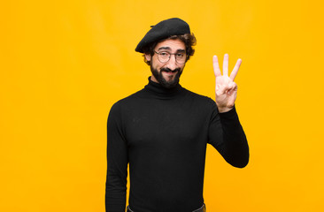 young french artist man smiling and looking friendly, showing number three or third with hand...