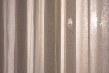 Translucent textile white monochrome curtains and a beam of light radiating through them