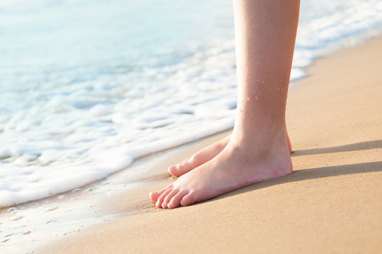Feet of a young woman on tropical beach. Surf sea and surise