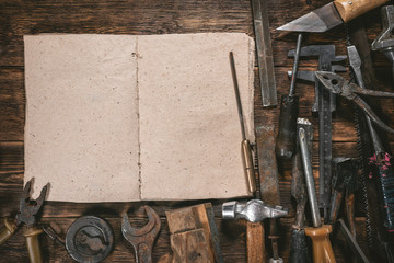 Carpentry or construction tips book with copy space and old tools on wooden workbench background.