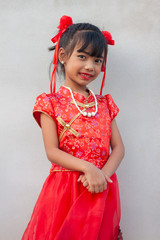 Happy chinese new year. Little girl stand pose and smiled brightly on cement wall background. 