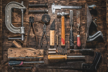 Old construction tools on a wooden workbench flat lay background. Carpenter table. Woodwork.