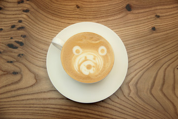 Cup of coffee with bear drawings on a wooden table