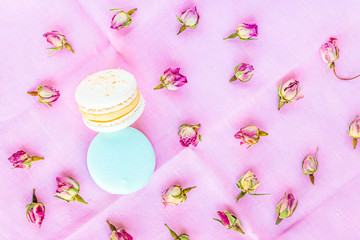 Top view at macarons and dried roses on pastel colour bakcground.