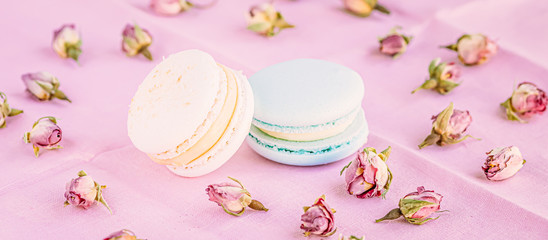 Selective focus on macarons with cream and the buds of dried roses.