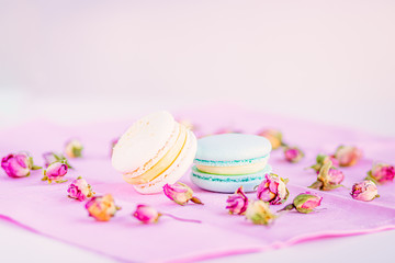 Selective focus on macarons with cream and the buds of dried roses.