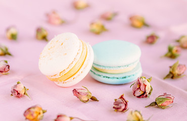 Selective focus on macarons with cream and the buds of dried roses.