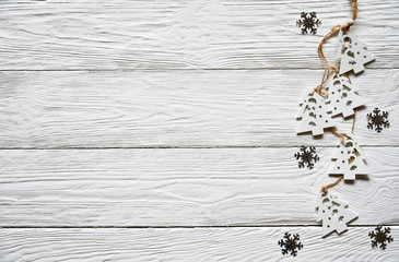 Fototapeta premium Christmas decorations on a white wooden background. White wooden fir trees on a lace and silver snowflakes. Winter background. Top view.