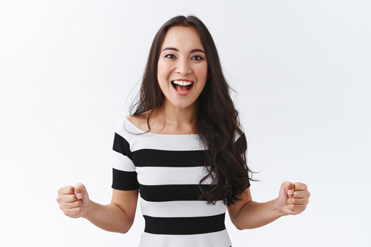 Luky, enthusiastic good-looking east-asian brunette girl motivated, determined win, clench fists empowered, smiling thrilled and joyful, feeling excited as watching thrilling game, white background