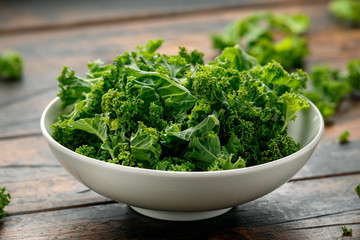 Raw Organic Kale in white bowl on wooden table