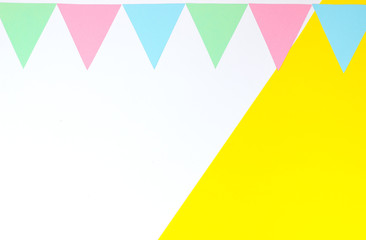 Colorful garland of paper triangles on a double yellow and white background. Greeting card. Flat lay style. Copyspace for text.